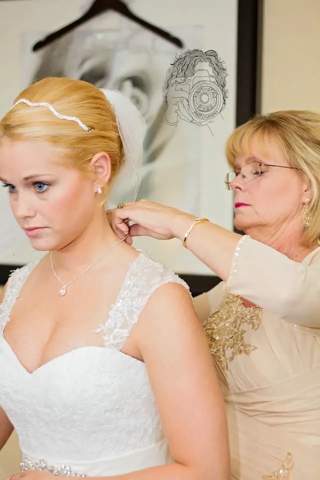 Mother of the bride helping bride get ready on wedding day ...